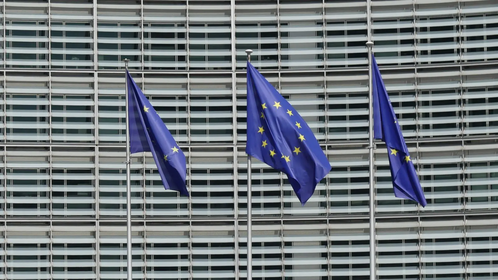 Trei steaguri ale Uniunii Europene în fața clădirii Berlaymont a Comisiei Europene din Bruxelles