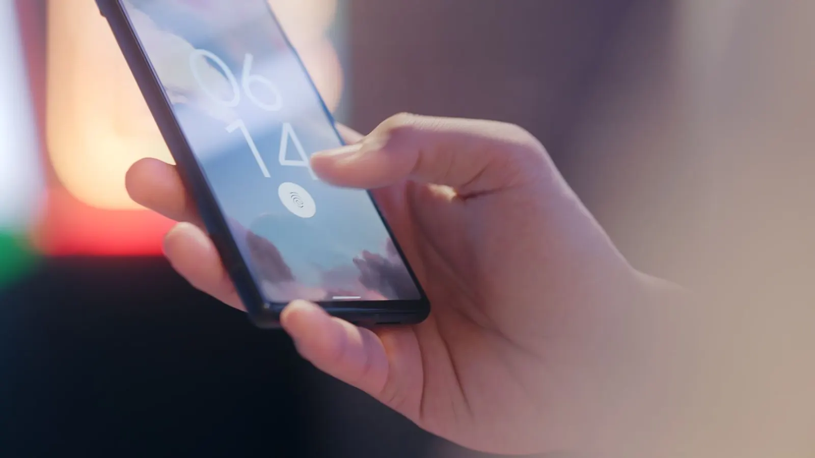 Mână care ține un telefon cu senzorul de amprentă afișat pe ecranul de blocare
