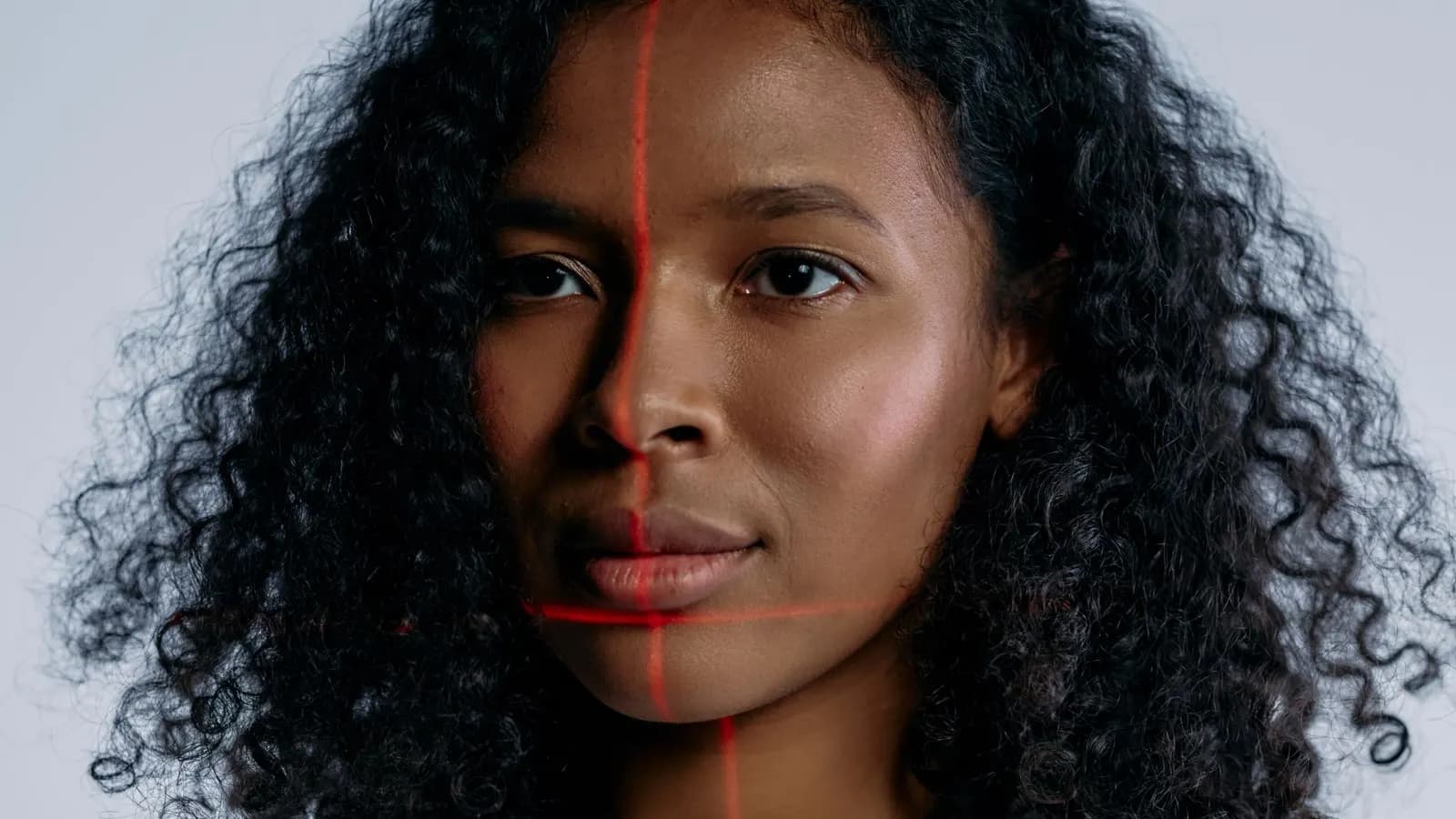 Portretul unei femei cu linii laser roșii de scanare facială pe chip