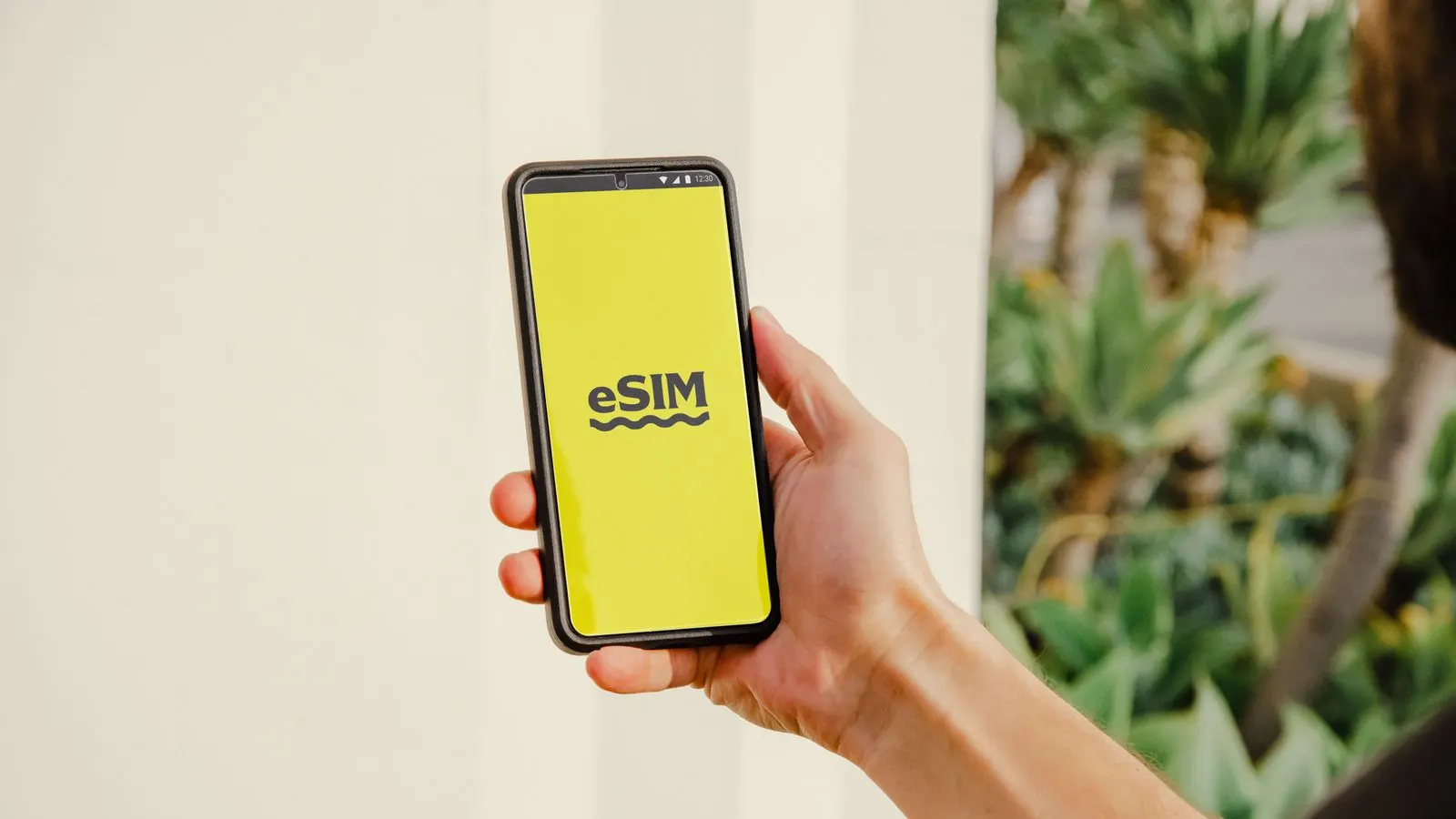 Mână care ține un smartphone cu inscripția eSIM pe ecran galben