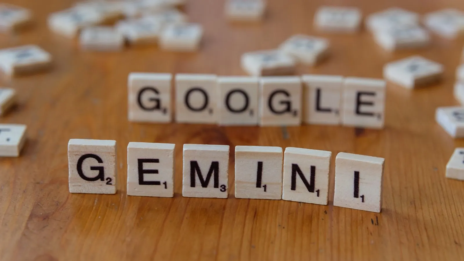 Piese de lemn de joc care formează cuvintele Google și Gemini pe o masă