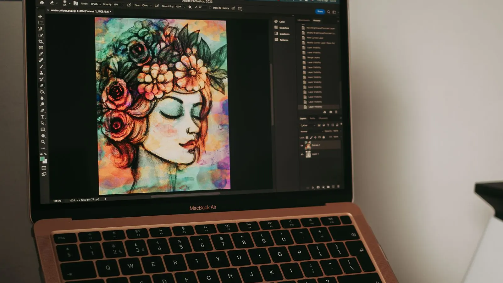 Laptop cu o ilustrație digitală colorată a unui portret de femeie cu flori