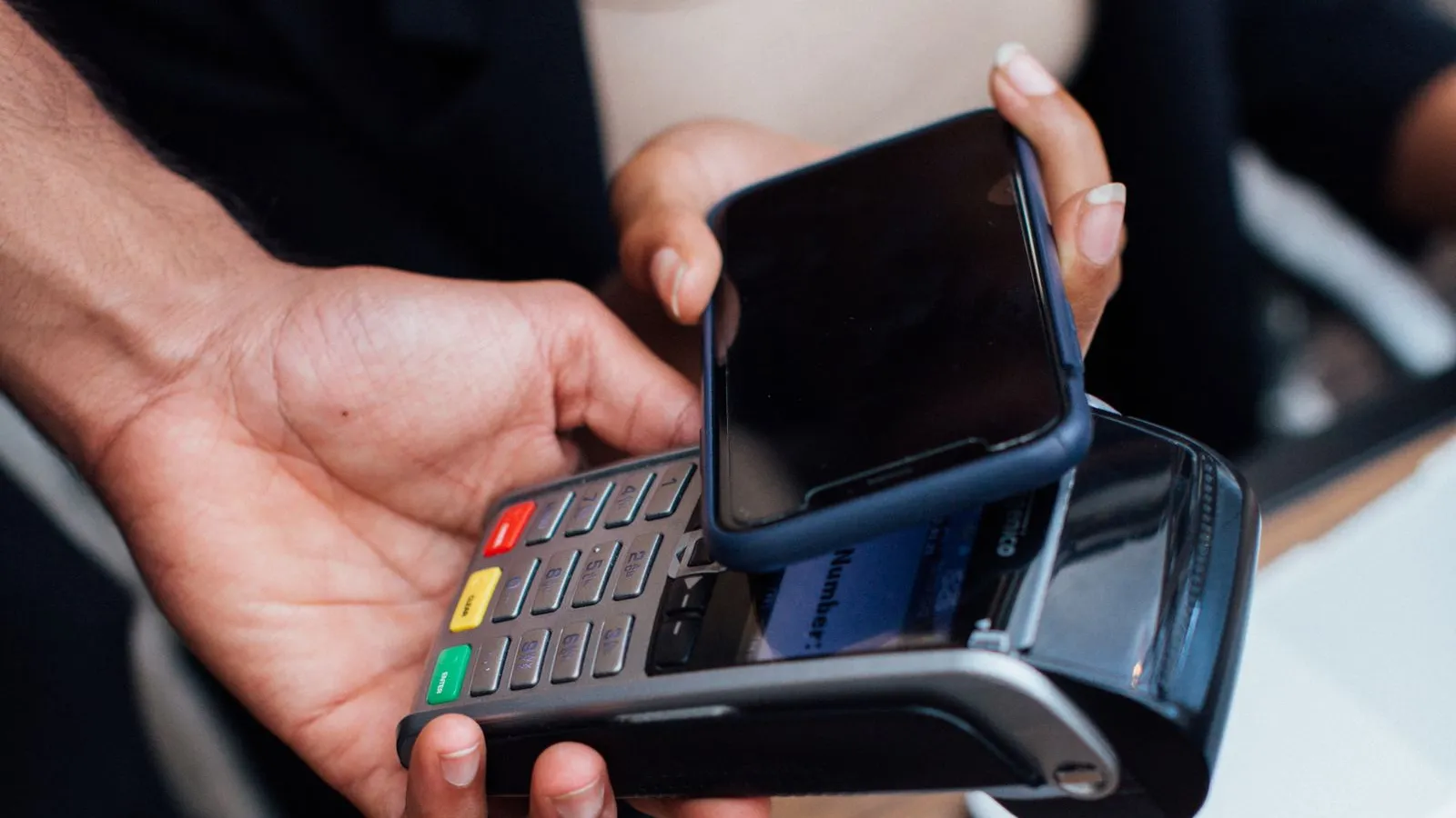 Plată cu telefonul apropiat de un terminal POS ținut în mână