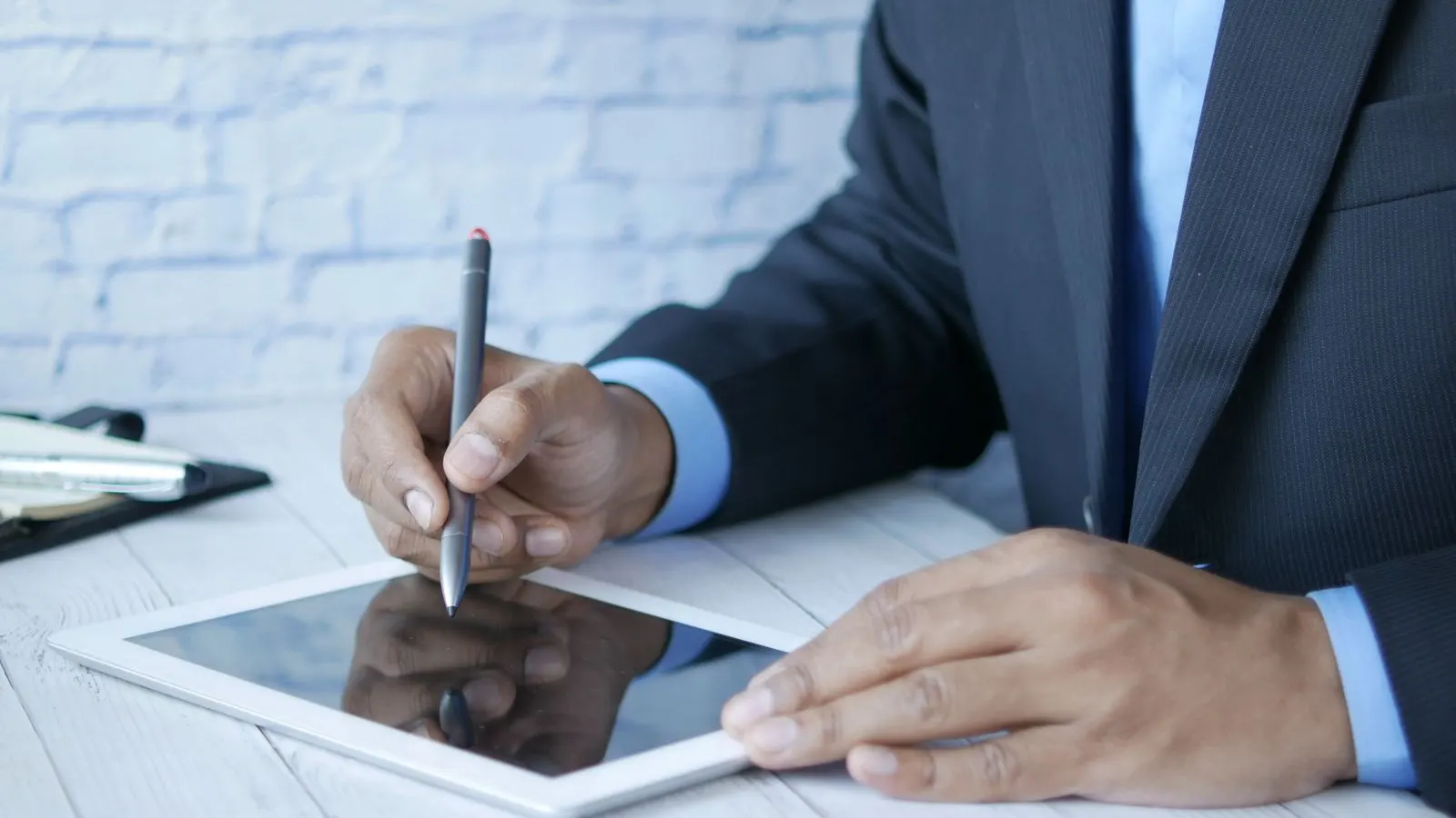 Bărbat la birou care semnează cu un stylus pe ecranul unei tablete
