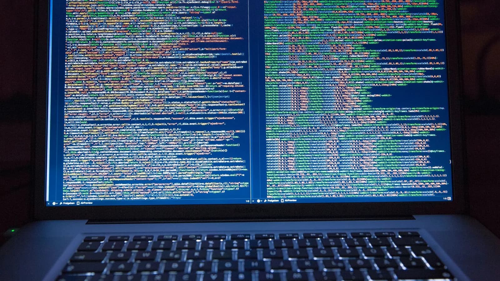 Laptop deschis într-o cameră întunecată, cu ecranul plin de cod sursă