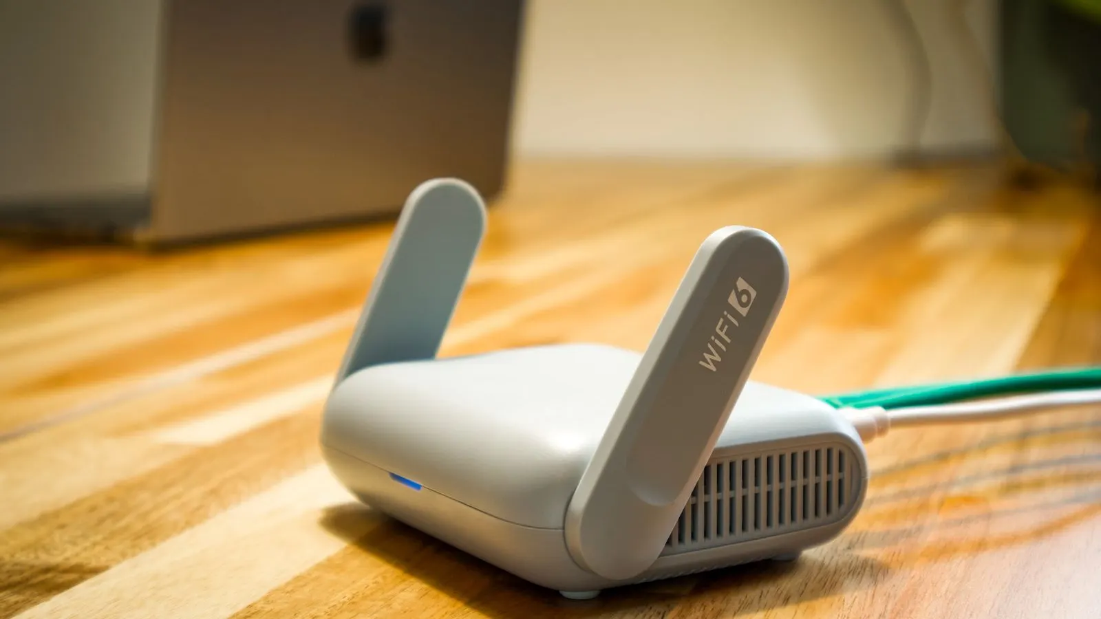 Router Wi-Fi 6 gri cu două antene, așezat pe un birou din lemn