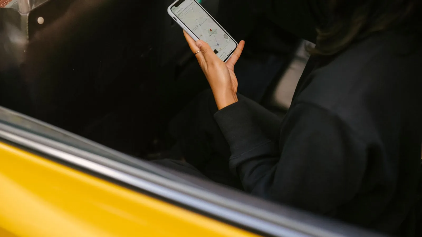 Pasageră într-un taxi galben se uită la o hartă pe ecranul telefonului