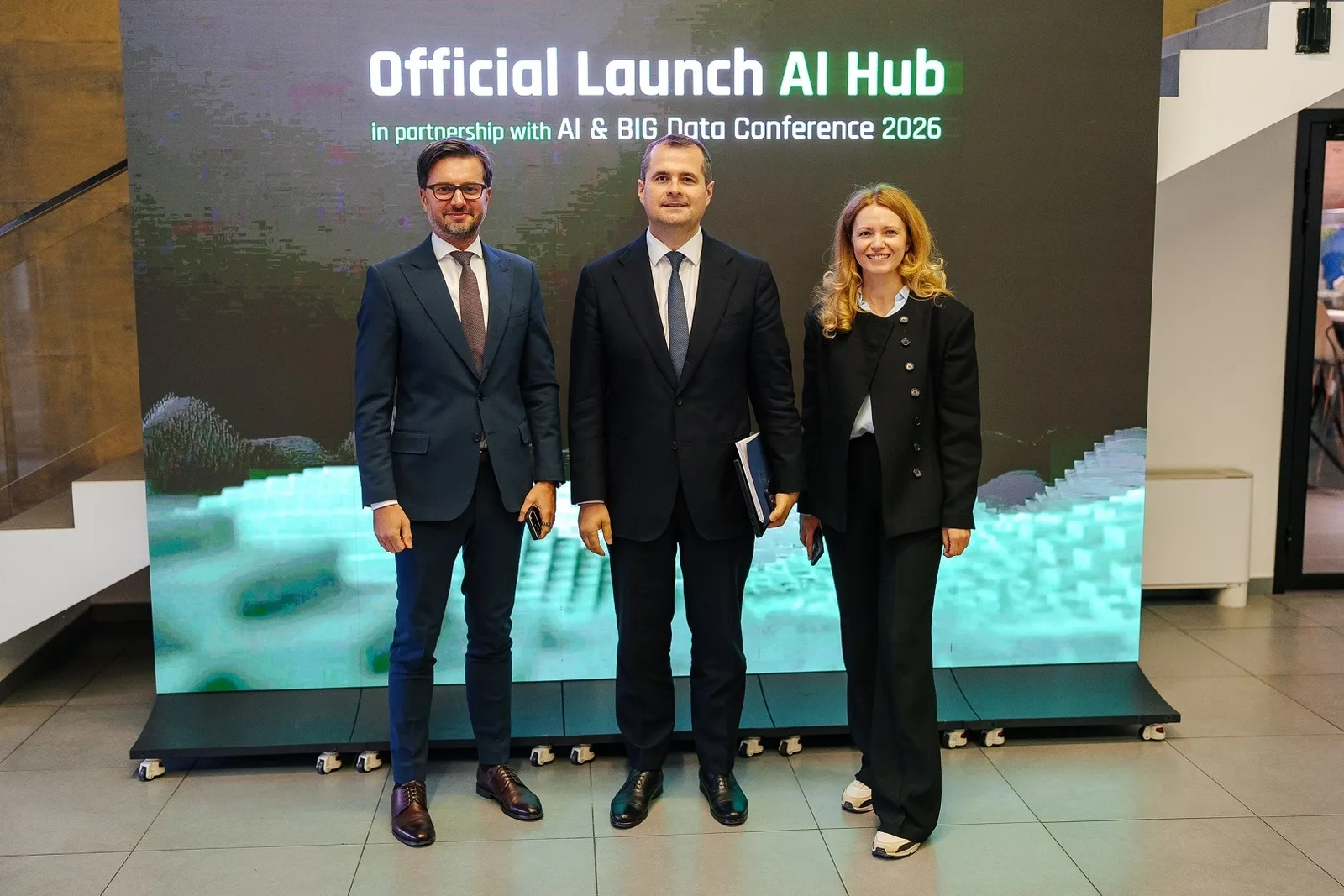 Premierul Vasile Tofan, alături de doi participanți, în fața ecranului cu inscripția „Official Launch AI Hub”